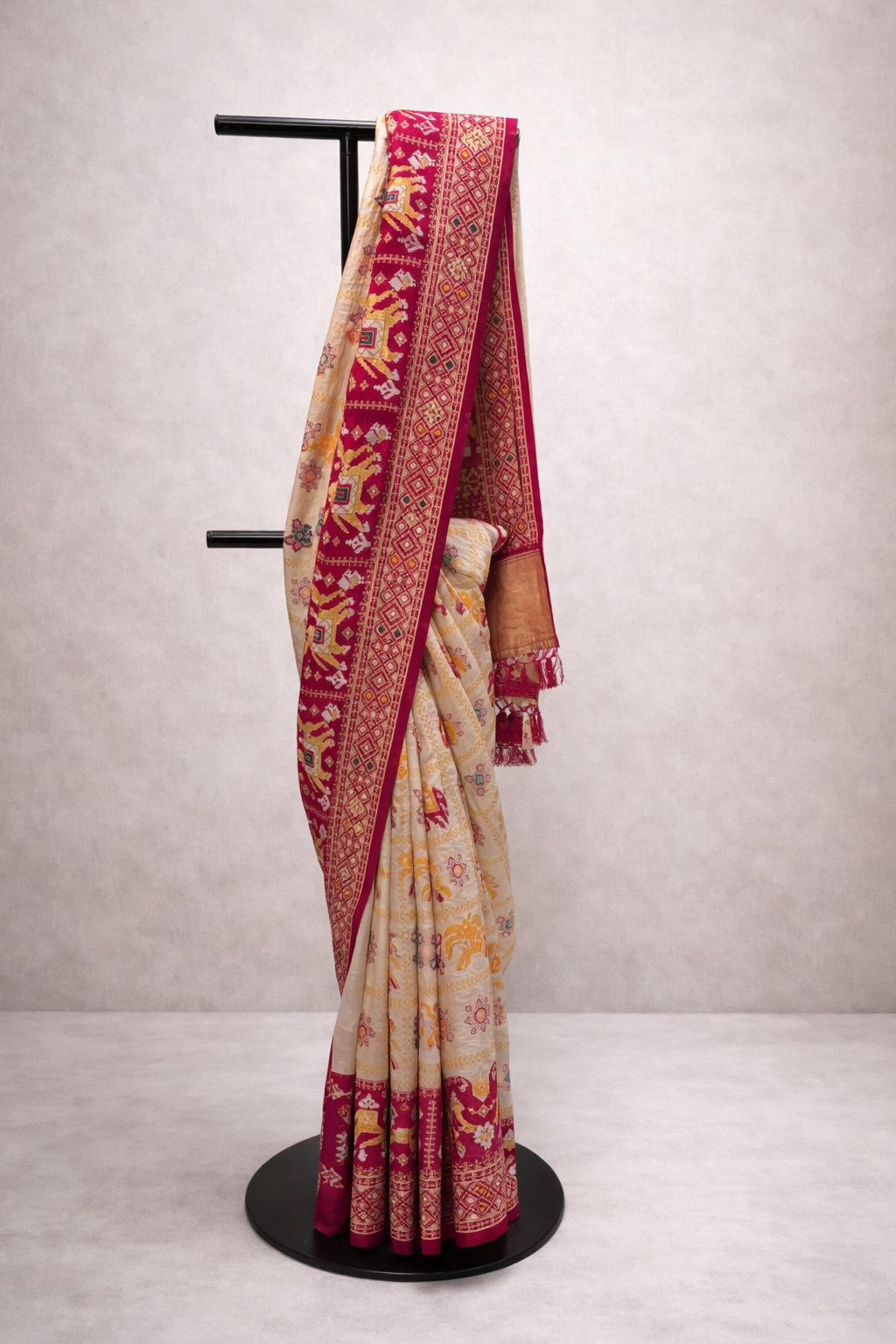 Saree with a red and gold border on a mannequin against a plain background