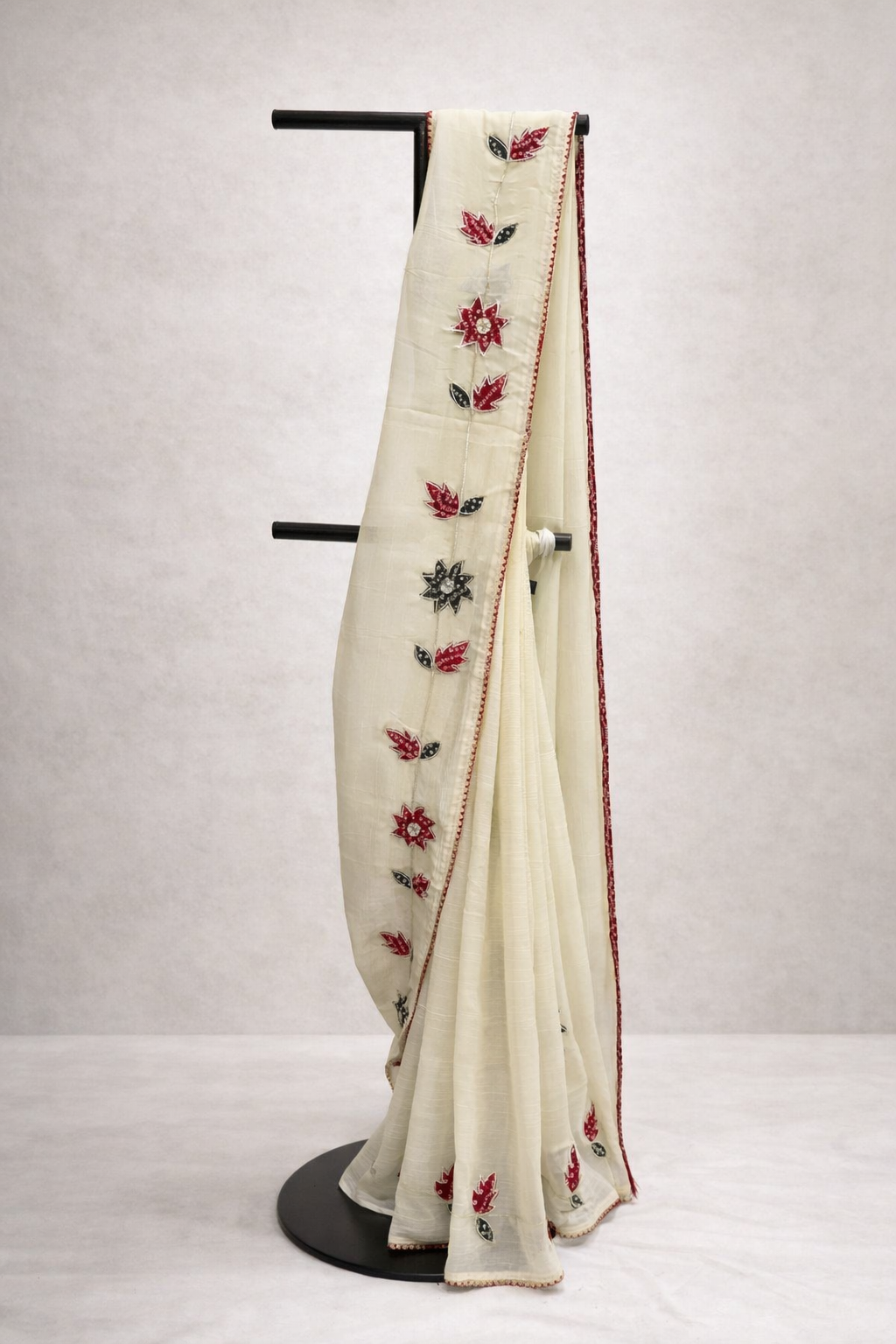 White saree with floral embroidery on a mannequin against a plain background