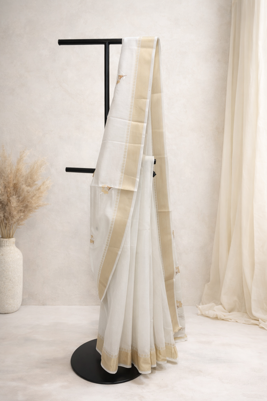 White saree with beige border on a black stand against a white background