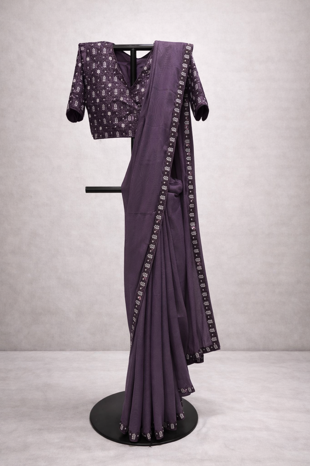 Purple saree with matching blouse on a mannequin against a gray background