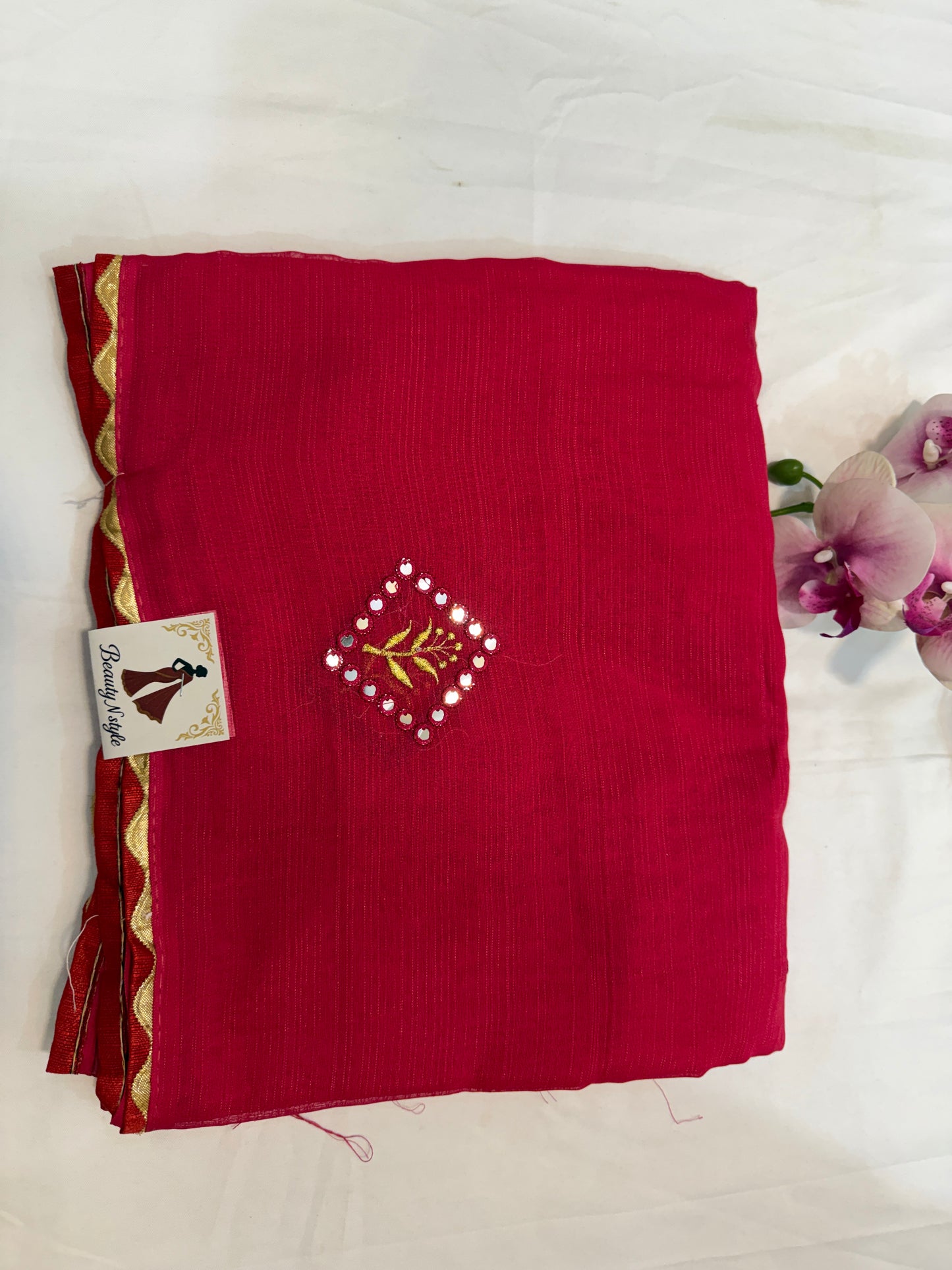 Red saree with gold border and floral embroidery on a white background